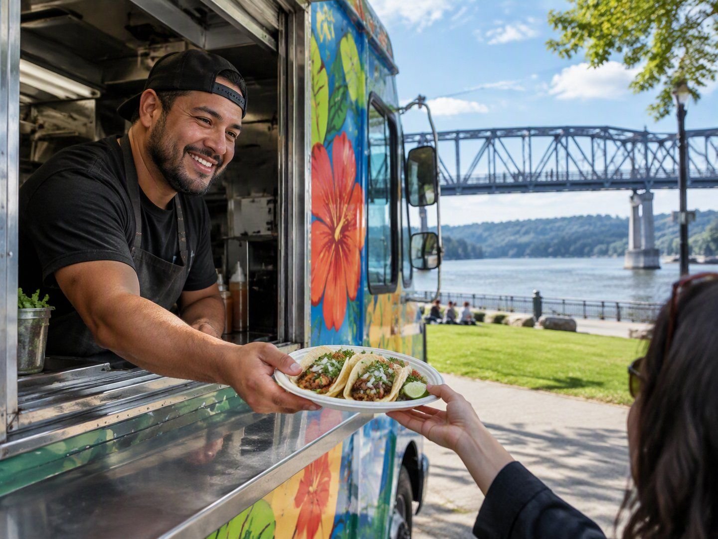 A Poughkeepsie food truck owner handing out tacos with the Walkway Over the Hudson bridge behind